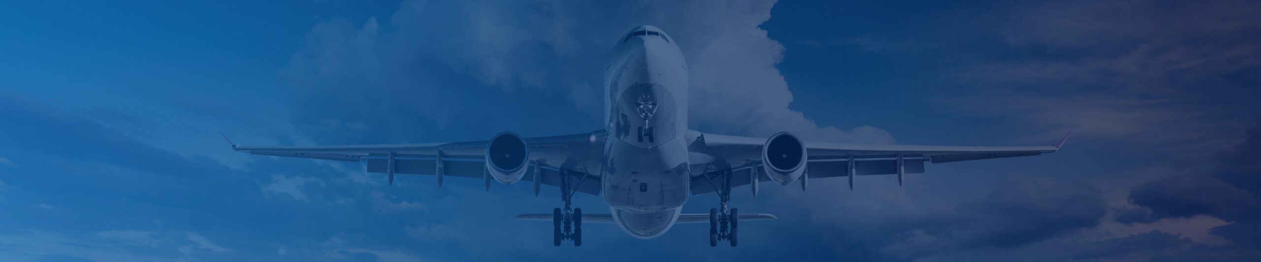 Two engine passenger aircraft with gear down taking off with cumulus clouds in the background.